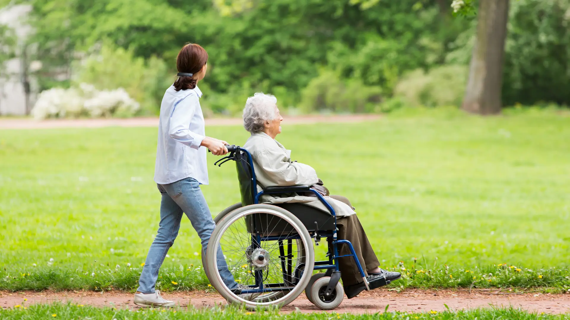 Assisted Living care worker pushing woman in wheelchair